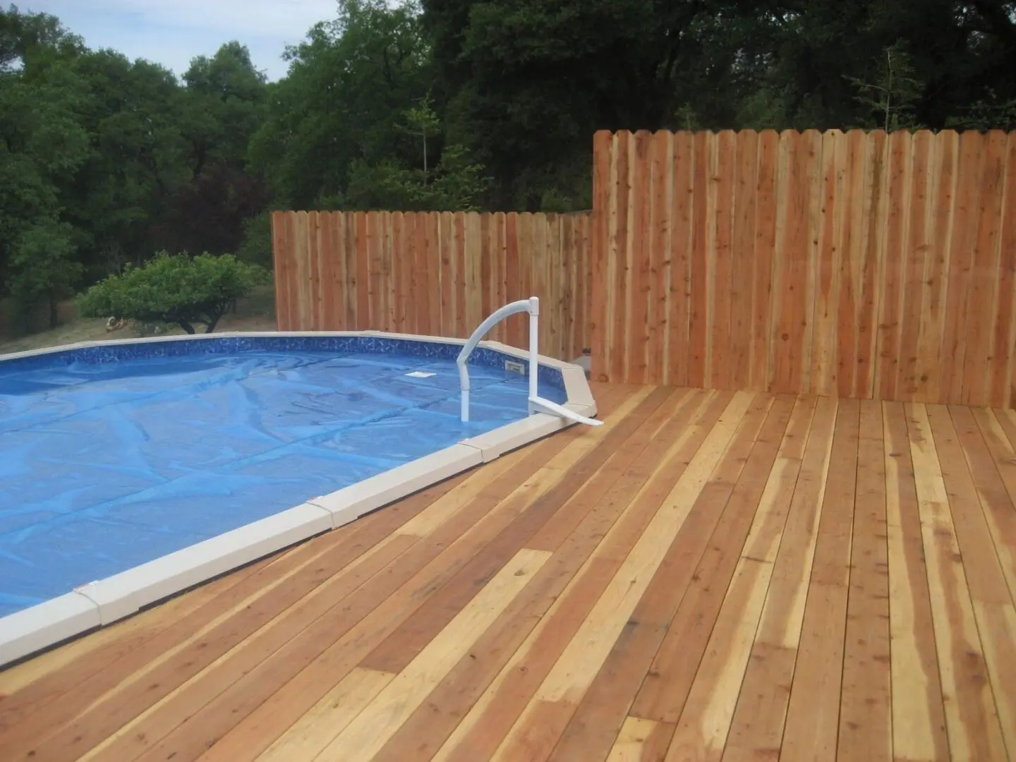 A pool with wooden deck and blue swimming pool.