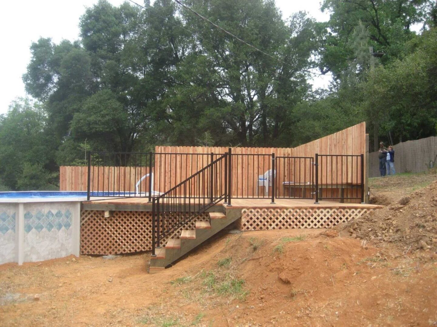A pool with stairs and fence in the background.