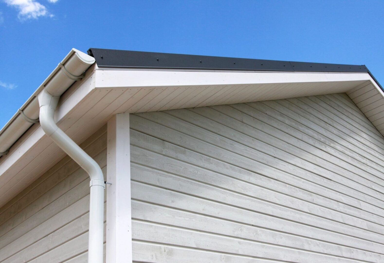 A close up of the corner of a house with a gutter